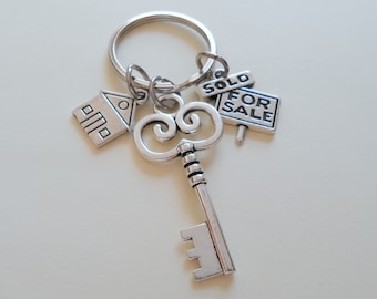 May include: Silver key chain with a house charm, a key charm, and a "SOLD FOR SALE" sign charm.