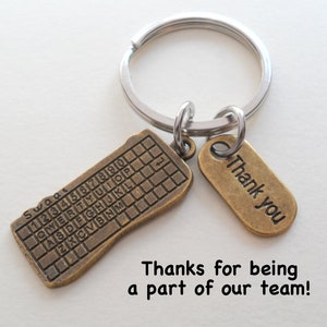 May include: A gold-toned keychain with a keyboard charm and a tag that says "Thank you".