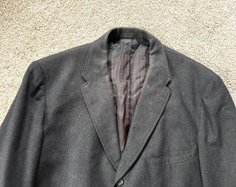 May include: A dark grey blazer with a single button closure and a pocket on the left side. The blazer has a striped lining.