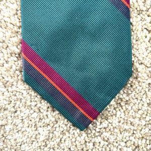 May include: A dark green tie with a diagonal stripe pattern in burgundy, orange, and navy blue.