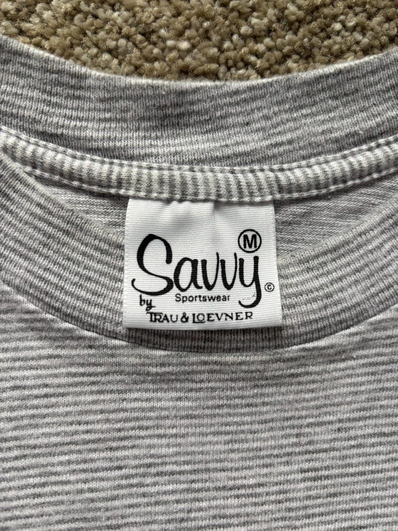 May include: Gray striped t-shirt with a white tag that says "Savvy Sportswear by Trau & Loevner" and has a size "M" label.