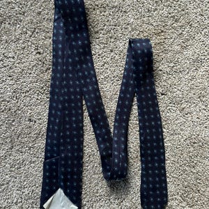 May include: A dark blue tie with a repeating pattern of small, light blue circles.