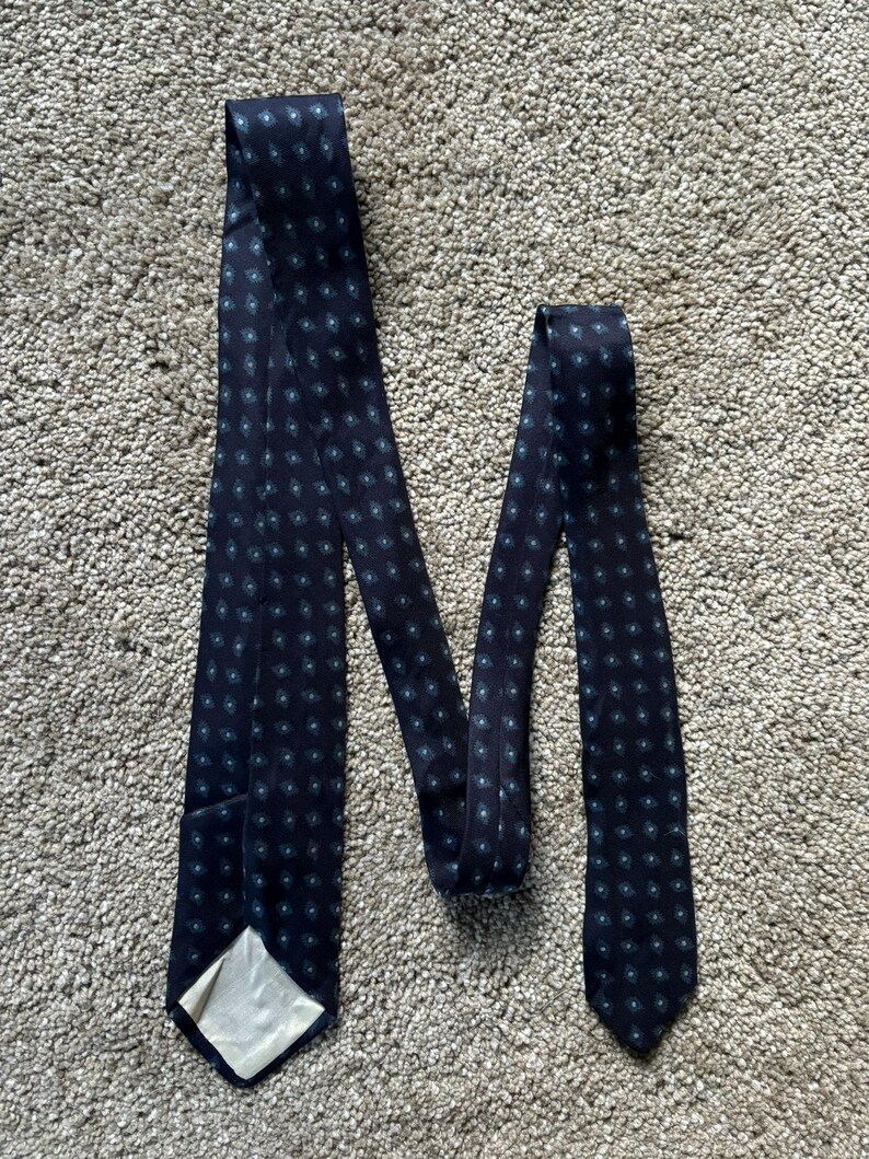 May include: A dark blue tie with a repeating pattern of small, light blue circles.