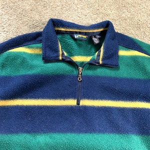 May include: A blue, green, and yellow striped fleece pullover with a quarter zip closure. The brand name "G-Tek" is visible on the tag.