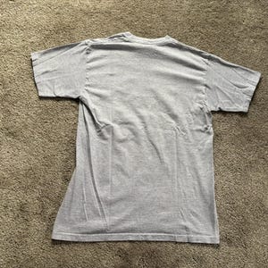 May include: A plain grey t-shirt with short sleeves.