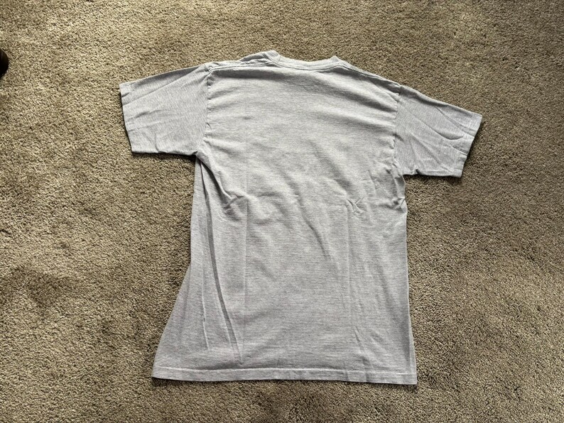 May include: A plain grey t-shirt with short sleeves.