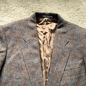 Può includere: Un blazer in tweed marrone con un motivo a spina di pesce e una fodera in raso marrone. L'etichetta riporta "Made in England".