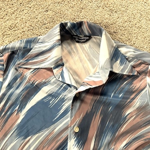 May include: A blue, pink, and white patterned shirt with a button-up collar and a label that reads "La Grande Bretagne".
