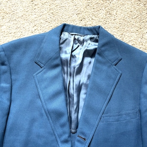 May include: A blue blazer with a satin lining. The blazer has a single button closure and a pocket on the right side.