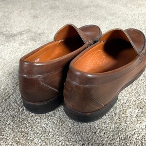 May include: A pair of brown leather loafers with a slip-on design. The loafers have a rounded toe and a slightly raised heel.