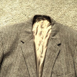 May include: A brown tweed blazer with a satin lining. The blazer has a classic style and a herringbone pattern.