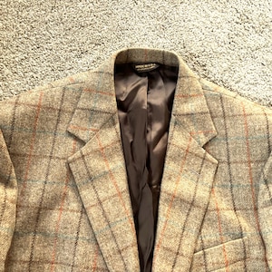 May include: A brown, gray, and orange plaid blazer with a black satin lining. The label reads "Made in U.S.A."