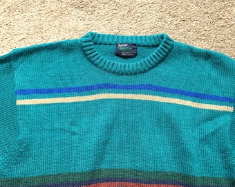 May include: A teal blue sweater with a white and blue striped pattern. The sweater has a crew neck and is made of acrylic. The label reads "Arrow Blazer 100% Acrylic Made in China."