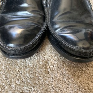 May include: A pair of black leather loafers with a stitched edge. The shoes have a polished finish.