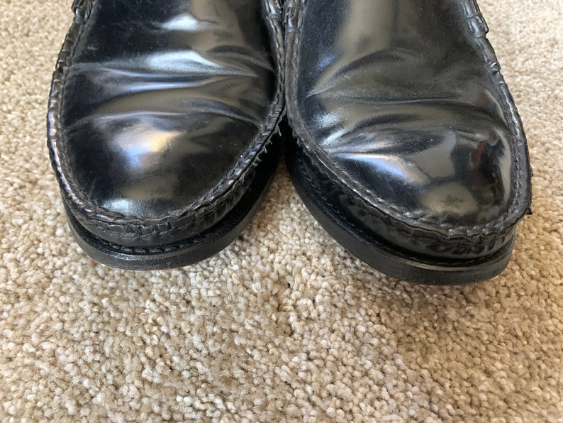 May include: A pair of black leather loafers with a stitched edge. The shoes have a polished finish.