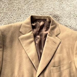 May include: A brown blazer with a notch lapel and a single button fastening. The blazer has a brown satin lining and a pocket on the left side.