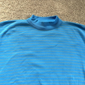 May include: A light blue, short-sleeved top with a mock turtleneck collar. The top has thin, light yellow horizontal stripes. The fabric appears to be a soft knit material. The top is suitable for casual wear.