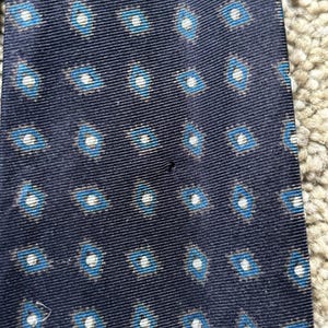 May include: A dark blue tie with a white and blue geometric pattern.