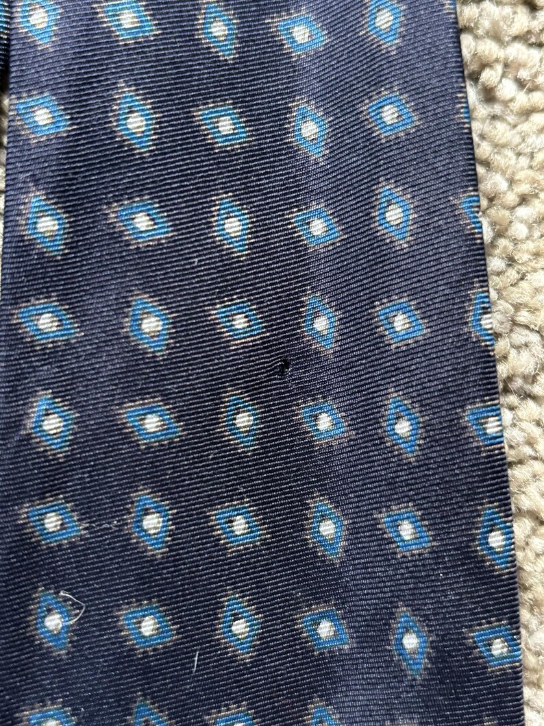 May include: A dark blue tie with a white and blue geometric pattern.