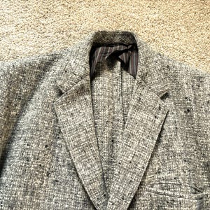 May include: A gray blazer with a speckled pattern. The blazer has a single button closure and a notched lapel.