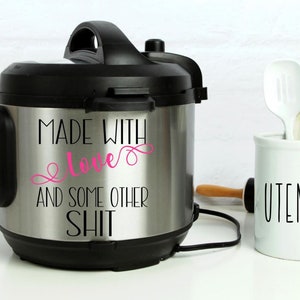 May include: A stainless steel Instant Pot with a black lid and handle. The pot has a sticker that reads "Made with love and some other shit". The word "love" is in pink lettering.