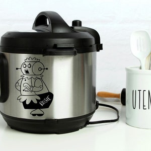 May include: A stainless steel electric pressure cooker with a black lid and handle. A black and white sticker of a robot with the name "Rosie" is on the front of the cooker.
