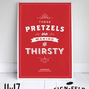 Può includere: Un poster incorniciato di 28 x 43 cm con sfondo rosso e testo bianco. Il testo recita "THESE PRETZELS are MAKING ME THIRSTY" con la citazione attribuita a Cosmo Kramer. Il poster è in una cornice bianca.