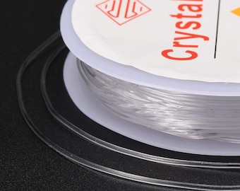 May include: A spool of clear elastic string for jewelry making. The spool is labeled "Crystal  Thread" and has a logo with a stylized "S" inside a diamond.