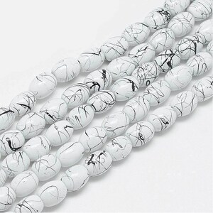 May include: White oval beads with black marbling. The beads are strung together in a long strand.