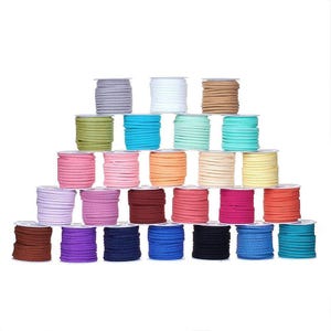 May include: A collection of spools of suede cord in various colors, including gray, white, tan, green, blue, pink, orange, and black. The cords are neatly wound on small spools, arranged in a pyramid shape against a white background.