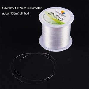 May include: A spool of clear monofilament illusion cord, approximately 0.2mm in diameter and 130 meters per roll. The label reads "MONOFILAMENT ILLUSION CORD" and "Not suitable for kids. Intended for adults only."