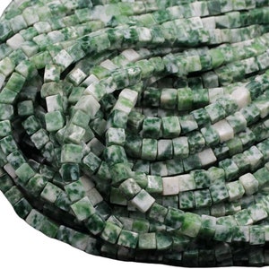 May include: A strand of green and white jade gemstone beads. The beads are square shaped and have a mottled appearance.