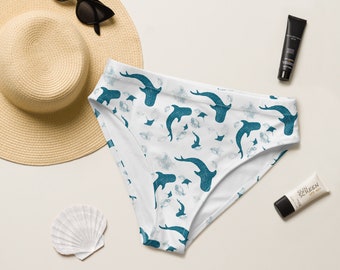 Puede incluir: Braga de bikini blanca con estampado de tiburón martillo azul. La braga tiene una pierna de corte alto y una cintura baja.