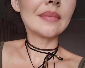 May include: A layered choker necklace with a small bird pendant. The necklace is made of black and brown leather cord and has a gold-tone finish.