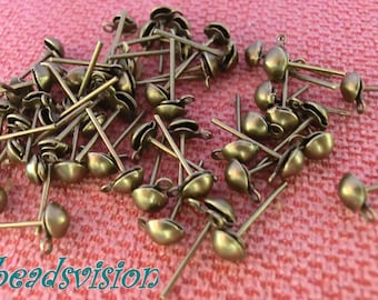 May include: A pile of gold-toned earring findings with a loop at the top and a post with a small ball at the end.