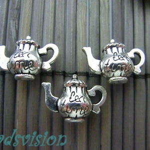 Könnte beinhalten: Drei silberne Teekannen-Anhänger mit der Gravur "tea time". Die Anhänger sind etwa 2,5 cm hoch und perfekt, um Ihren Schmuck oder Ihren Bastelarbeiten einen Hauch von Verspieltheit zu verleihen.