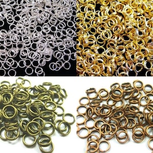 Op de afbeelding: Een grote hoeveelheid springringen in vier verschillende kleuren: zilver, goud, brons en koper. De ringen zijn allemaal even groot en zijn gerangschikt in stapels.
