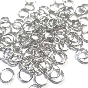 Op de afbeelding: Een grote stapel zilveren springringen. De ringen zijn klein en rond en liggen allemaal in een hoop.