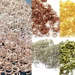 Könnte beinhalten: Eine Sammlung von Sprungringen in vier verschiedenen Farben: Silber, Gold, Kupfer und Grün. Die Sprungringe sind klein und rund und perfekt für die Schmuckherstellung.