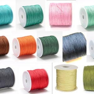 Könnte beinhalten: Spulen mit gewachstem Baumwollgarn in verschiedenen Farben, darunter Türkis, Grün, Rosa, Hellgrün, Braun, Orange, Dunkelgrün, Blau, Hellblau, Grau, Rot, Gelb und Olivgrün.