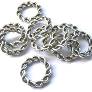 Könnte beinhalten: Eine Gruppe silberfarbener Metall-Sprünge mit geflochtenem Design. Die Ringe liegen auf einem weißen Hintergrund.