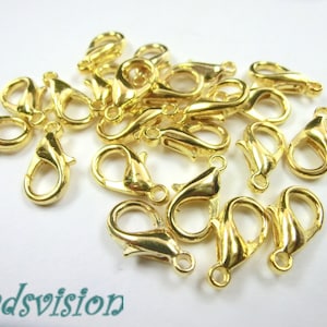 May include: A group of 20 gold-toned metal lobster claw clasps. The clasps are about 1 inch long and have a shiny finish.