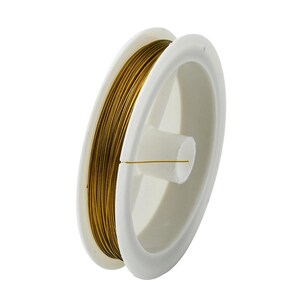 Può includere: Un rocchetto di filo color oro su un'aspo di plastica bianca.