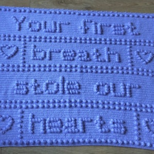Puede incluir: Una manta de bebé de crochet color lavanda con el texto "Your first breath stole our hearts" en letras en relieve.