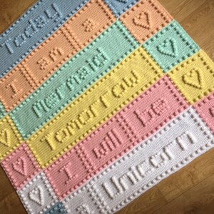 May include: A colorful crocheted baby blanket with a rainbow of colors and the words "Today I am", "Not ready", "Tomorrow", "I will be", and "Unicorn" in raised lettering.