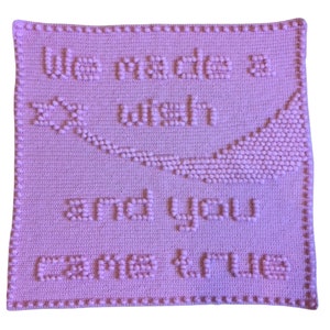 May include: A pink crocheted blanket with the text "We made a wish and you came true".