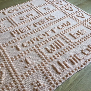 May include: A peach-coloured crocheted baby blanket with the text "You are my sunshine, you are my heart, you are my everything, you will be loved forever" in raised lettering.