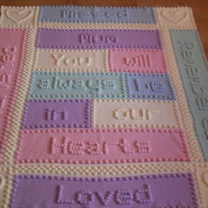 May include: A crocheted baby blanket in pastel colours. The blanket features the words "Missed you Mum, You will always be loved in our hearts, Loved".