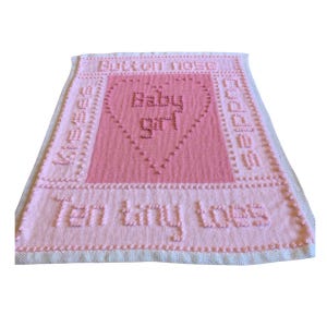 May include: Pink knitted baby blanket with the words "But on nose" and "Ten tiny toes" and a heart with the words "Baby girl" in the center.