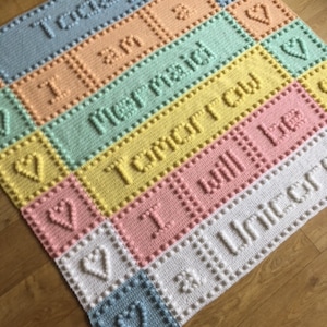 May include: A multi-coloured crocheted baby blanket with the words "Today I am", "Tomorrow I will be", and "A Unicorn" in white.